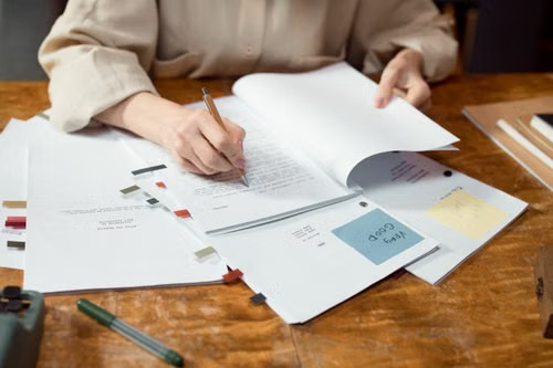 Editor reviewing printed financial education content pages at a desk